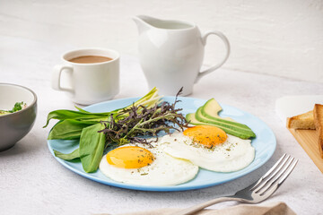 Plate with tasty fried eggs, coffee and greens on light table