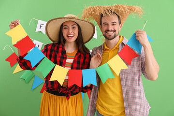 Young couple with flags on green background. Festa Junina (June Festival) celebration