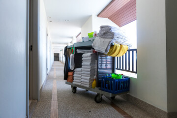The hotel cleaning tool cart of housekeeper are on the walkway of resort area. Cleaners trolley on...