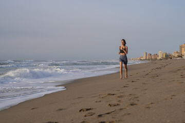 beautiful young girl running in the morning on the beach