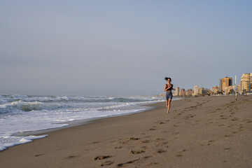 beautiful young girl running in the morning on the beach