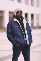 Portrait fashionable black man wearing denim jacket, hoodie, sunglasses and knitted hat. Cool...