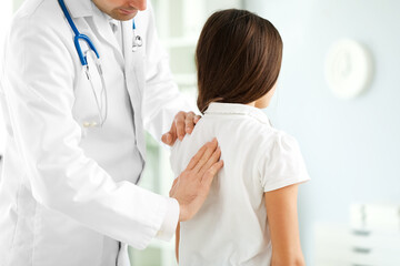 Doctor checking posture of little girl in clinic