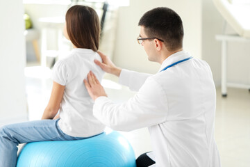 Doctor checking posture of little girl in clinic