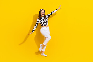 Obraz na płótnie Canvas Full length photo of excited pretty girl wear cow skin shirt having fun arms sides empty space isolated yellow color background