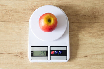 Fresh red apple on white kitchen scales in the kitchen view from above. The concept of proper nutrition and healthy lifestyle