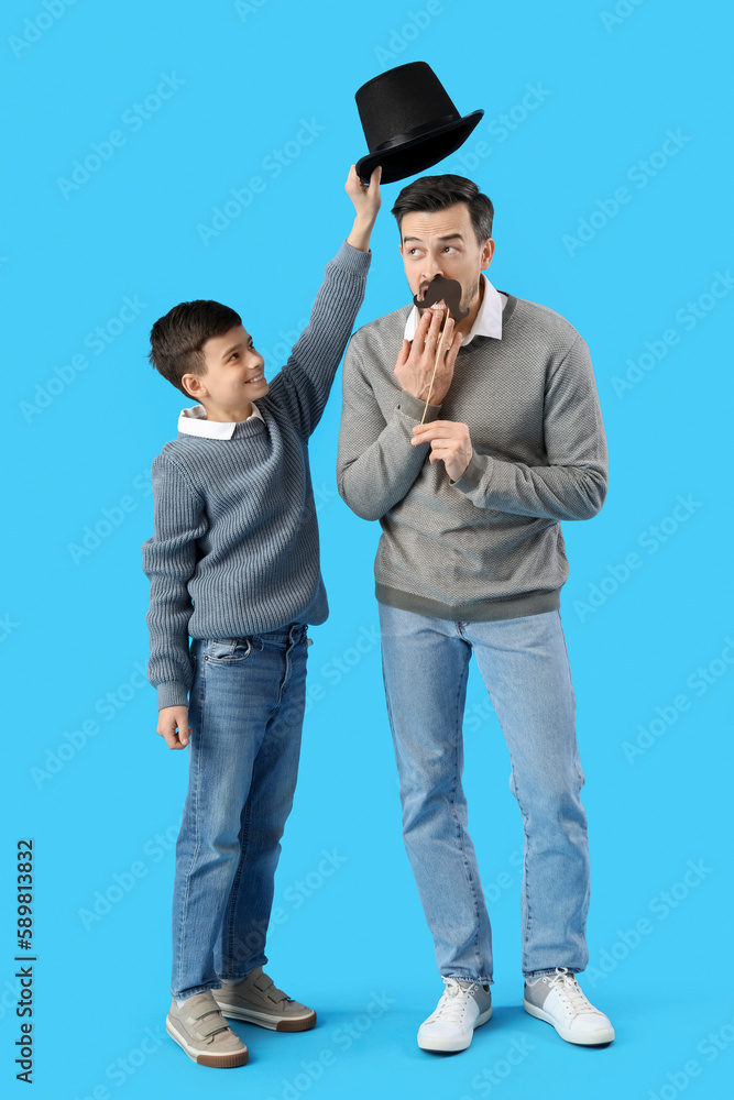 Poster portrait of father and his little son with paper mustache and hat on light blue background