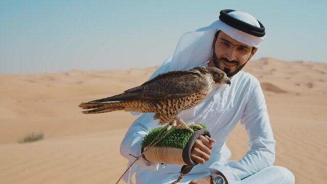 Falconer training his falcon bird in the desert of Dubai. Locals spending time on the dunes in Sharjah. Concept about traveling in the united arab emirates