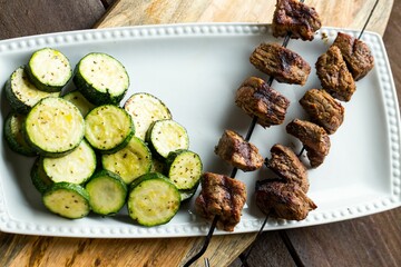 Closeup of a Steak Shish Kababb with a barbecued zucchini side dish