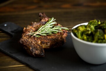 Beef steak and bowl of broccolis on a board