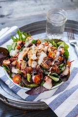 Bowl with gourmet salad on a towel in a metal tray