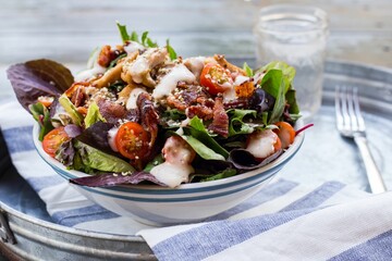 Bowl with gourmet salad on a towel in a metal tray