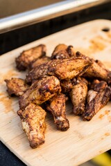 Vertical shot of grilled chicken wings on a wooden board