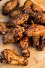 Vertical shot of grilled chicken wings on a wooden board