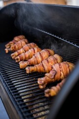 Grill with chicken legs wrapped in bacon