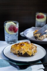 Selective focus of a steak with melted cheese on a ceramic plate served with water with ice cubes