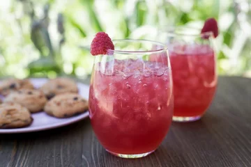 Tuinposter Closeup of red strawberry lemonades with ice put on the table with cookies on blurred background © Jeffrey Bethers/Wirestock Creators