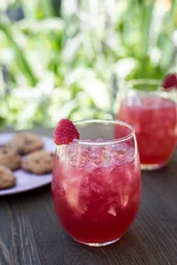 Poster Closeup of red strawberry lemonades with ice put on the table with cookies on blurred background © Jeffrey Bethers/Wirestock Creators