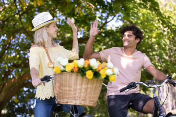 couple are giving high five while cycling in the park