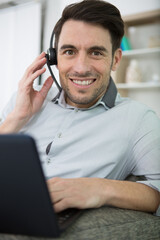 man wearing a headset with microphone and using a laptop
