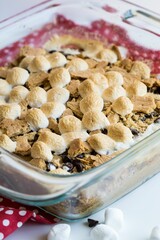 Vertical closeup shot of the marshmallow dessert in a glass bowl on a red fabric with white circles