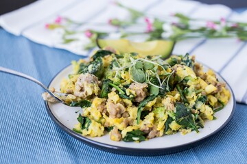 The salad with eggs and avocado on a plate with a fork on a fabric decorated with small flowers