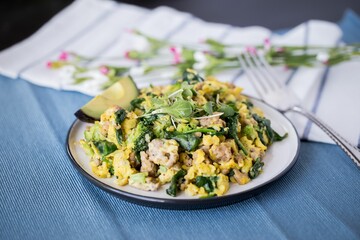 The salad with eggs and avocado on a plate with a fork on a fabric decorated with small flowers
