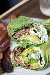 Vertical closeup shot of the lettuce wraps with bacon and avocado on a gray plate on a wooden table