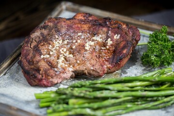 Closeup of the seasoned steak on a tray with greens on a blurry background