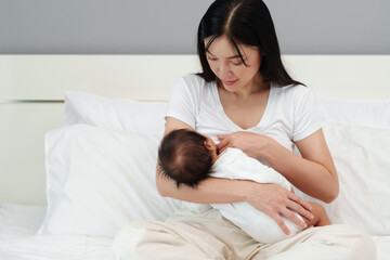 mother breastfeeding newborm baby on bed - obrazy, fototapety, plakaty
