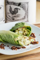 Bacon wrapped in lettuce leaves put on the white plate on the wooden table