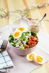 Healthy breakfast salad with eggs and fresh vegetables with a cup of tea on the blurred background