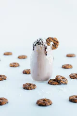 Schilderijen op glas Closeup shot of a delicious cookie shake in a glass jar surrounded by cookies © Jeffrey Bethers/Wirestock Creators