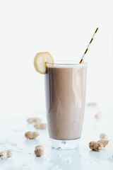 Closeup shot of a delicious cookie shake in a tall glass cup surrounded by peanuts