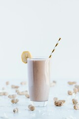 Closeup shot of a delicious cookie shake in a tall glass cup surrounded by peanuts