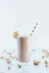 Fotobehang Closeup shot of a delicious cookie shake in a tall glass cup surrounded by peanuts © Jeffrey Bethers/Wirestock Creators