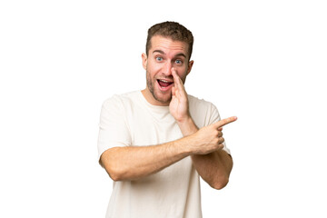 Young handsome caucasian man isolated on green chroma background pointing to the side to present a...