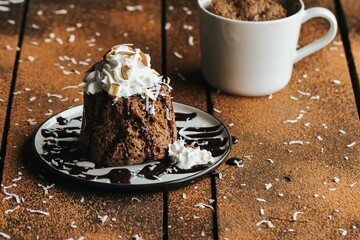 Closeup shot of a chocolate cake and a white cup on the wooden background