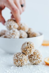 Vertical shot of coconut bites and oranges on the white background