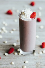 Closeup shot of a delicious strawberry milkshake in a tall glass cup surrounded by strawberries