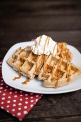Closeup shot of waffles topped with whipped cream and drizzled with peanut butter
