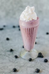 Vertical closeup shot of a glass of triple berry shake with cream on the top