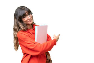 Young student caucasian woman over isolated background pointing back