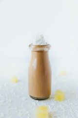 Vertical closeup of a glass of chocolate milkshake on a table, with cream on top