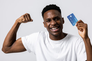 Portrait of african young student guy celebrating smiling holding new credit card advertisement of...