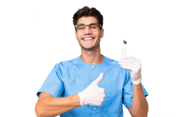 Young dentist man holding tools over isolated background giving a thumbs up gesture
