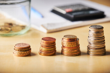 stacks of coins from different countries on the background of a notebook for notes and a calculator