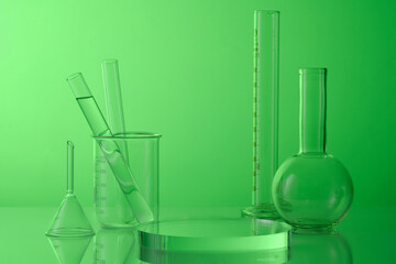 Science and medical background with lab glassware - test tubes, boiling flask, beaker and round transparent podium on green background. Blank space for product presentation.