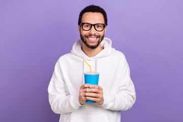 Portrait of young smile man wear pullover new glasses hold plastic cup drinking coke fresh lemonade isolated on purple color background