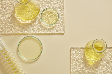 Flat lay of erlenmeyer flasks, petri dish and a test tube with spiral pipe inside containing yellow...